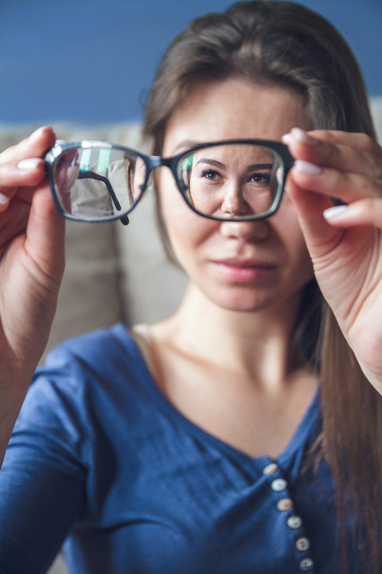 A woman with vision problems hold eyeglasses